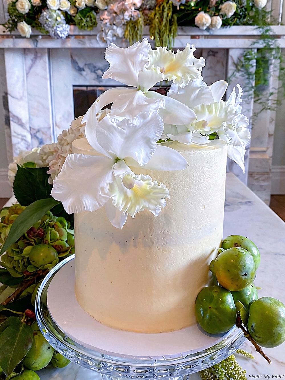 A beautifully styled wedding cake adorned with fresh white orchids, providing an elegant inspiration for a sage and pastel wedding palette.
