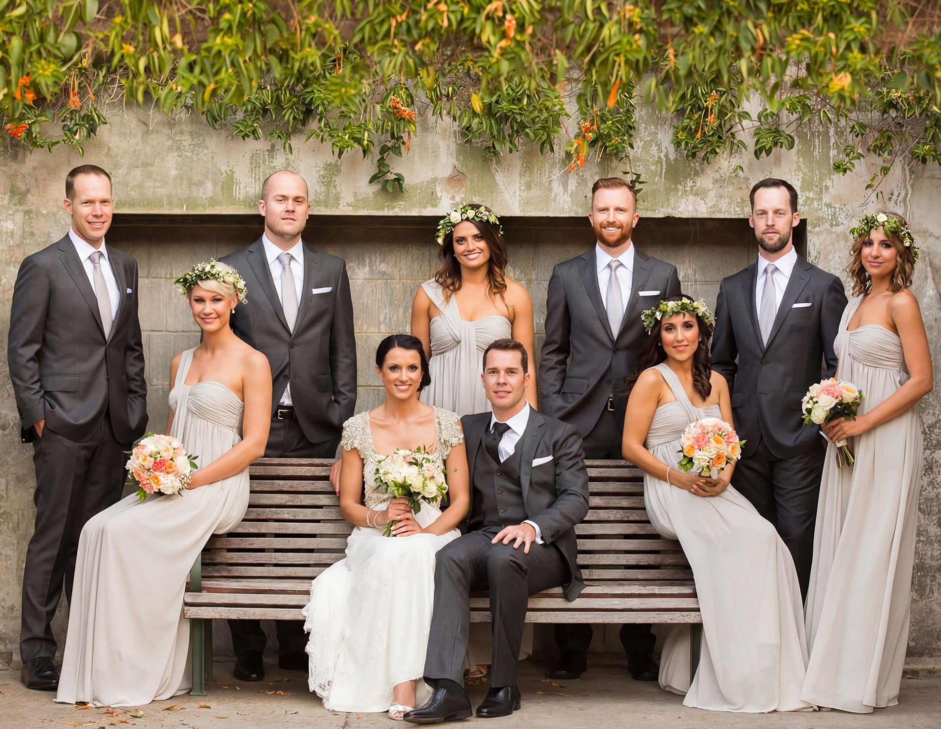 Full bridal party portrait featuring the bride, groom, groomsmen, and bridesmaids in elegant grey attire.