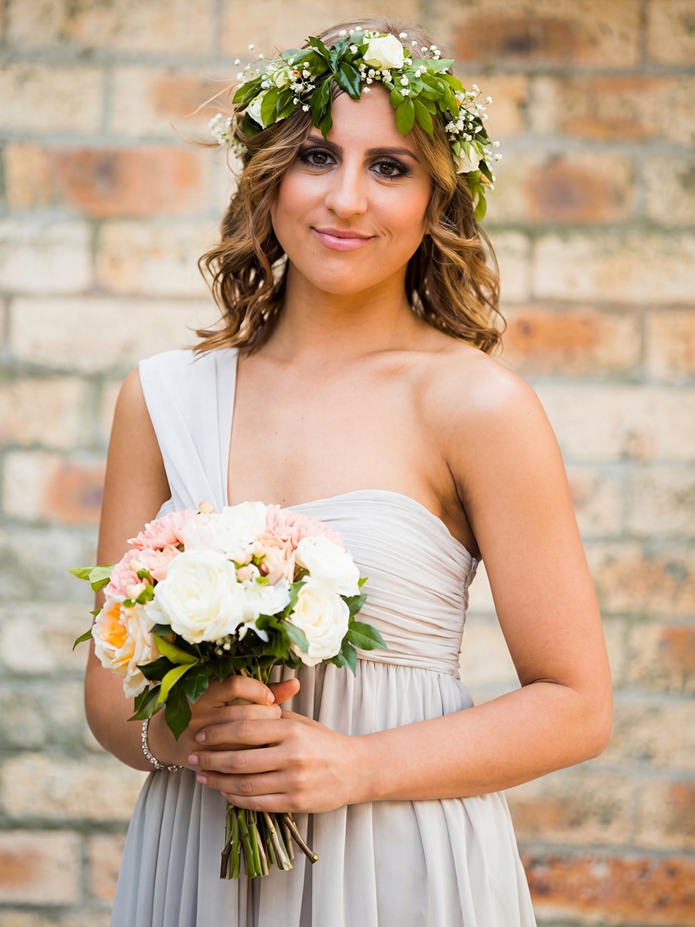 Close up portrait of a bridesmaid wearing our beautifully tailored grey chiffon one-shoulder gown.