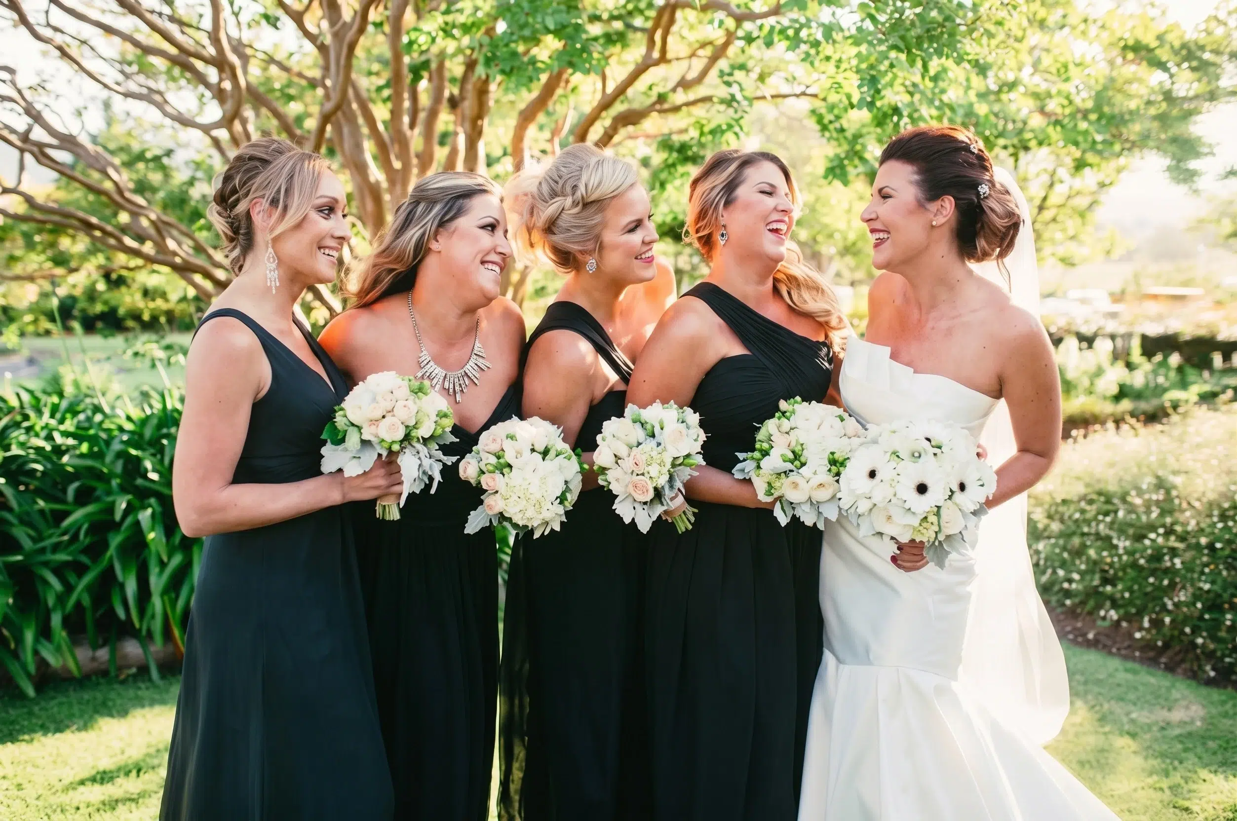 Real bride Kara celebrating with her bridesmaids in beautifully tailored, mix-and-match black bridesmaid dresses.
